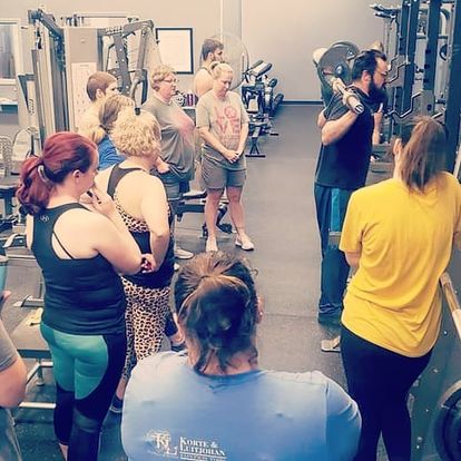 Josh showing his clients how to safely and properly squat with weights in the gym.