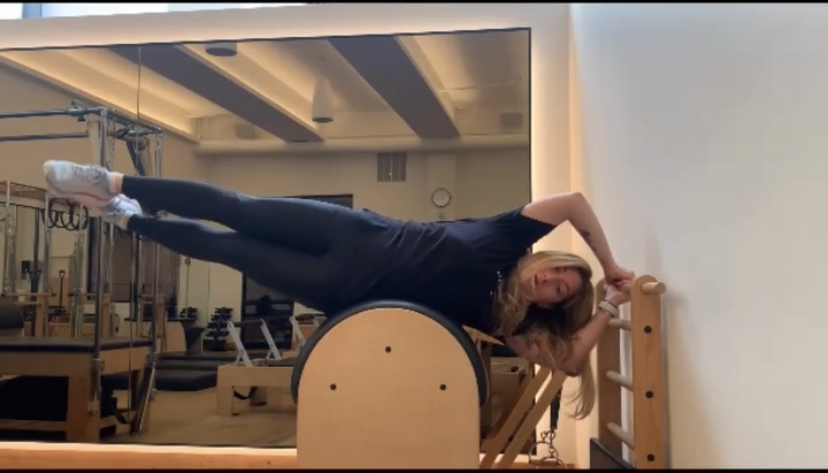 Ashley demonstrating how to use a pilates machine in a studio for a class.