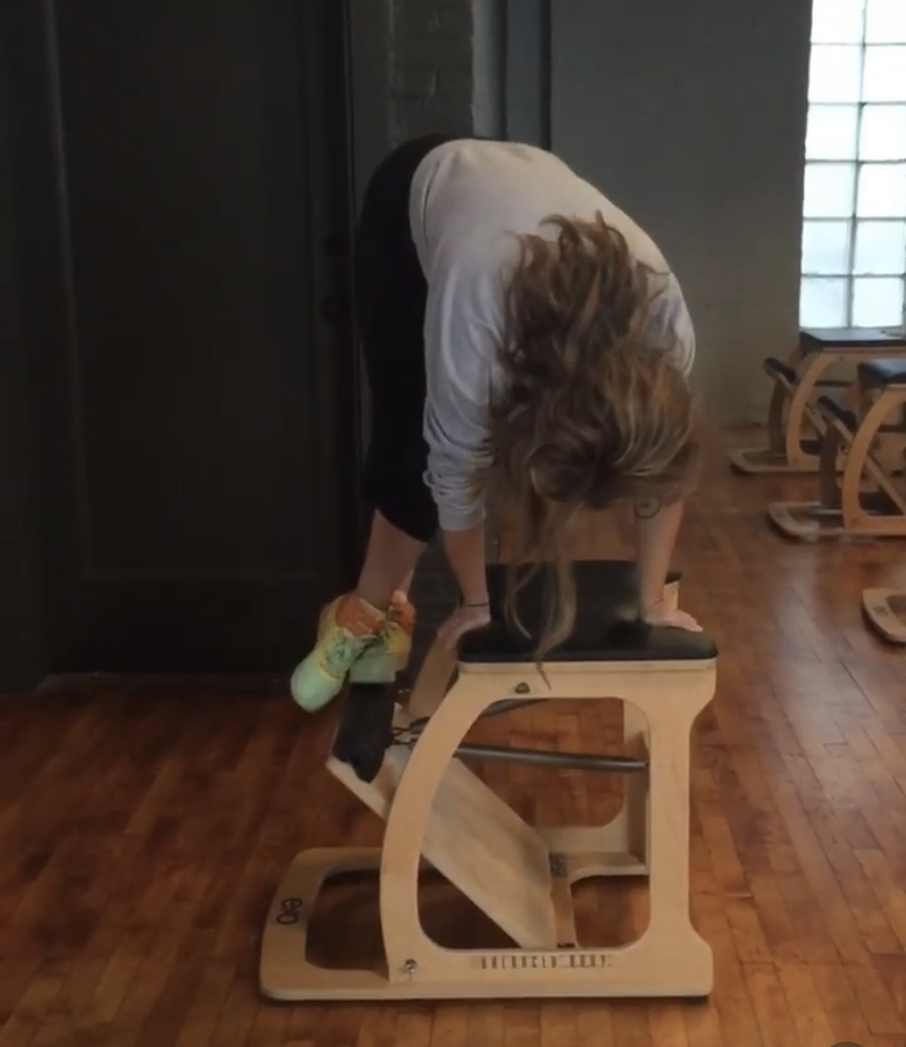 Ashley doing a workout on her hands using a pilates machine that helps her strengthen her core.