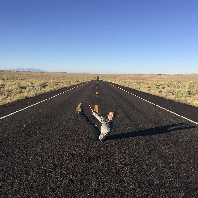 Ashley striking a yoga pose in the middle of an empty road in the desert.