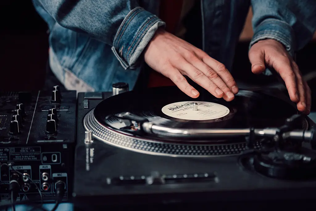 A close-up shot of a DJ at a turntable playing a vinyl record.