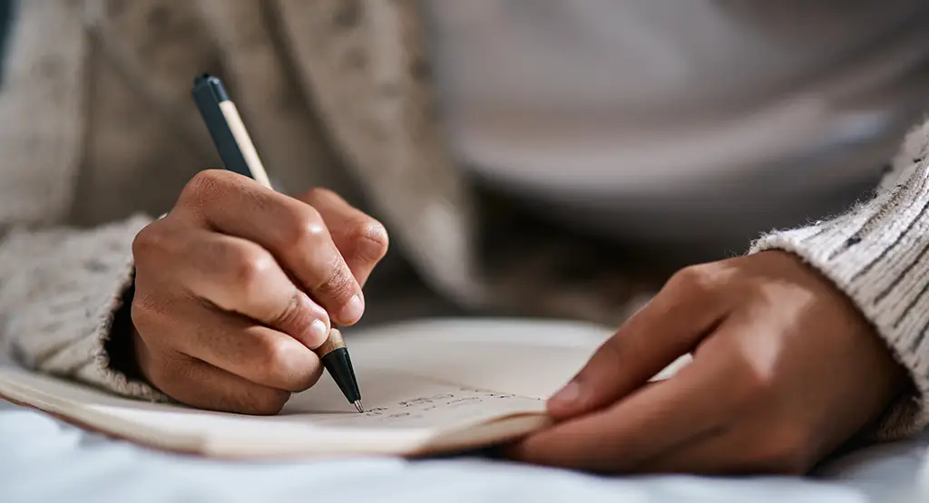 Up-close view of hands writing in a notebook