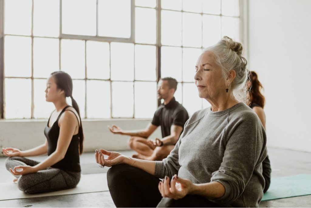 diverse ages and people meditating in studio together