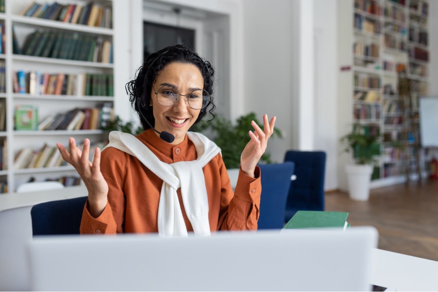 online tutor at computer with headset talking animatedly