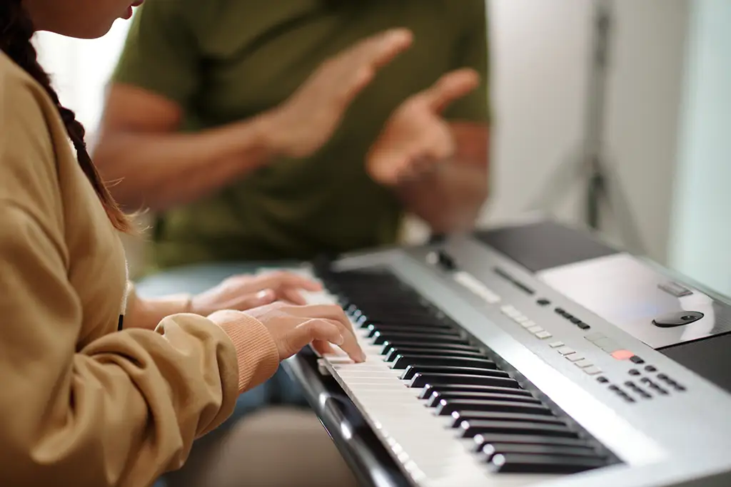Music teacher with student playing piano