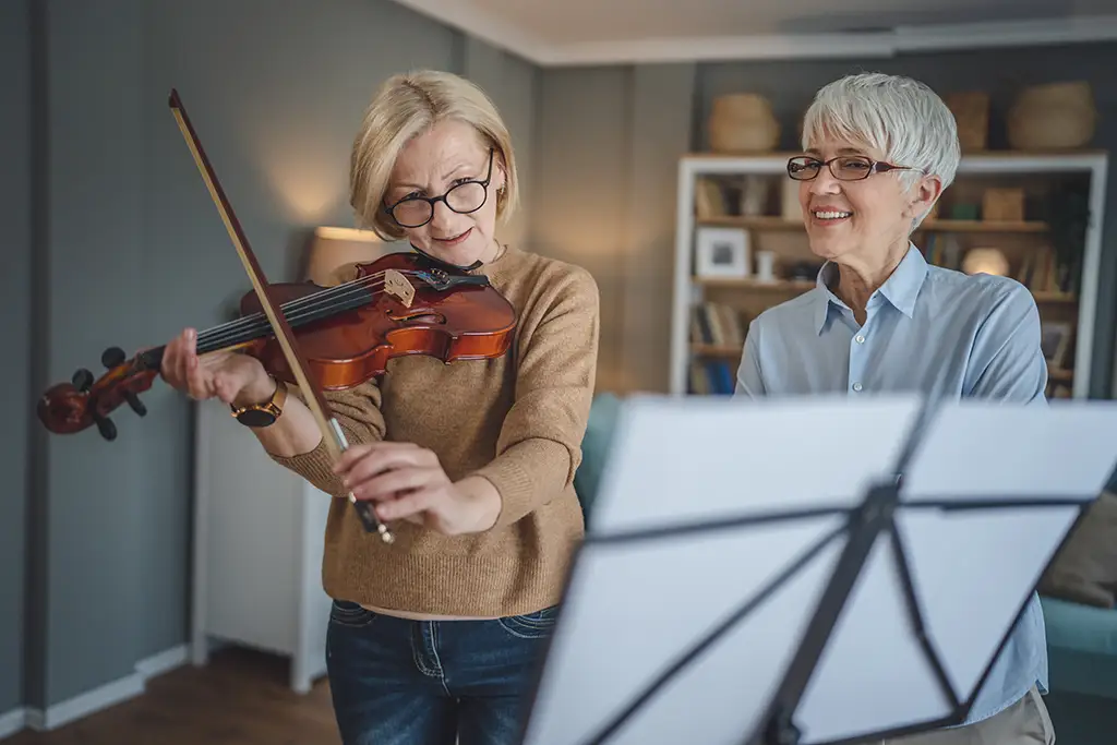 Private music teacher lesson with two women learning violin.