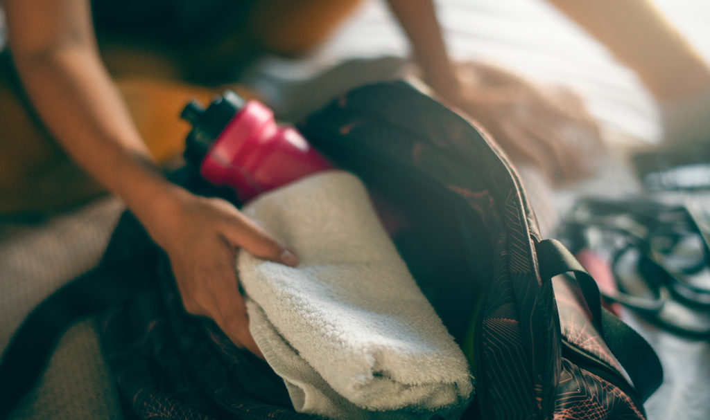 A person is packing workout gear into a bag to take to a training session with a client.