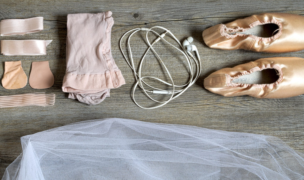 Different items needed for a ballet dancer's costume are neatly laid out on the ground.