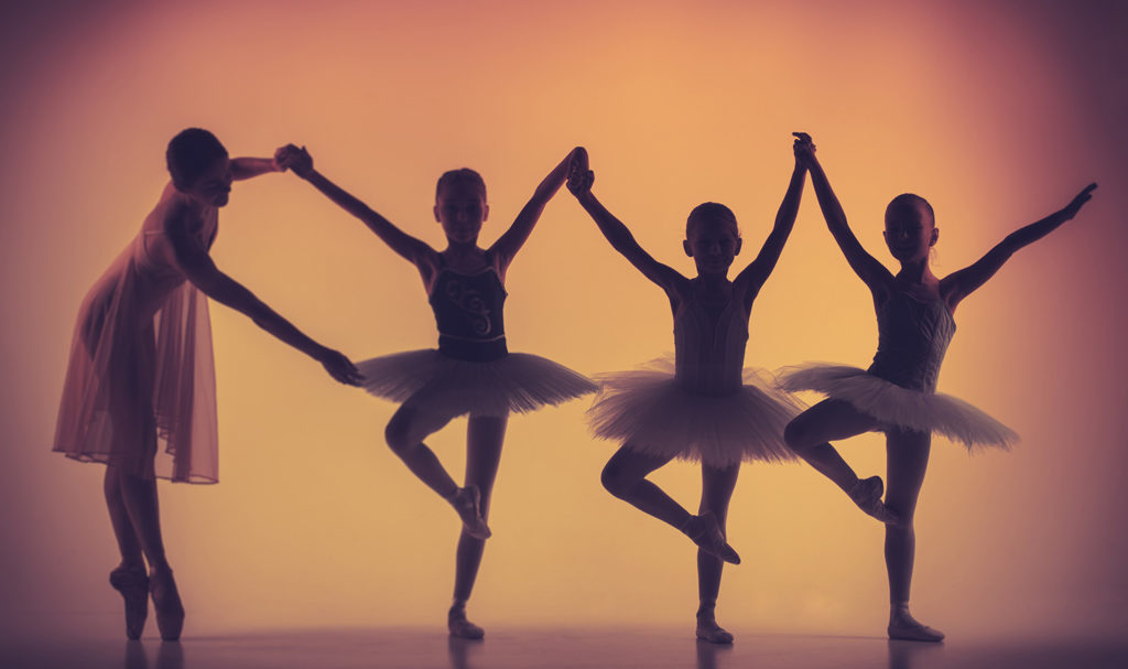 A group of ballerinas pose with the help of their dance teacher.