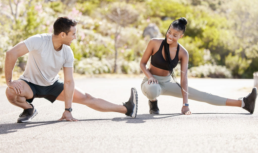 A fitness instructor and client are stretching before an outdoor run.