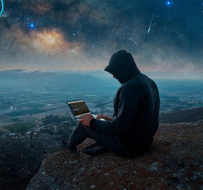 A person in a hoodie buys insurance from a laptop at night on a mountain.