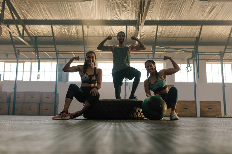 a fitness team flexes together in a gym.