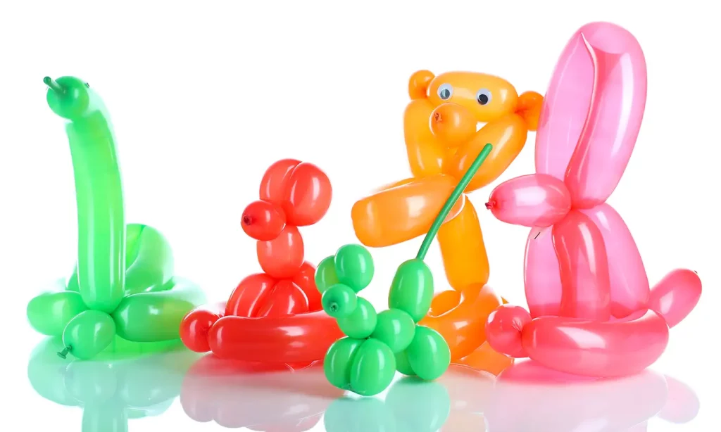 A variety of colorful balloon animals in front of a white background, including an orange monkey and a green snake.