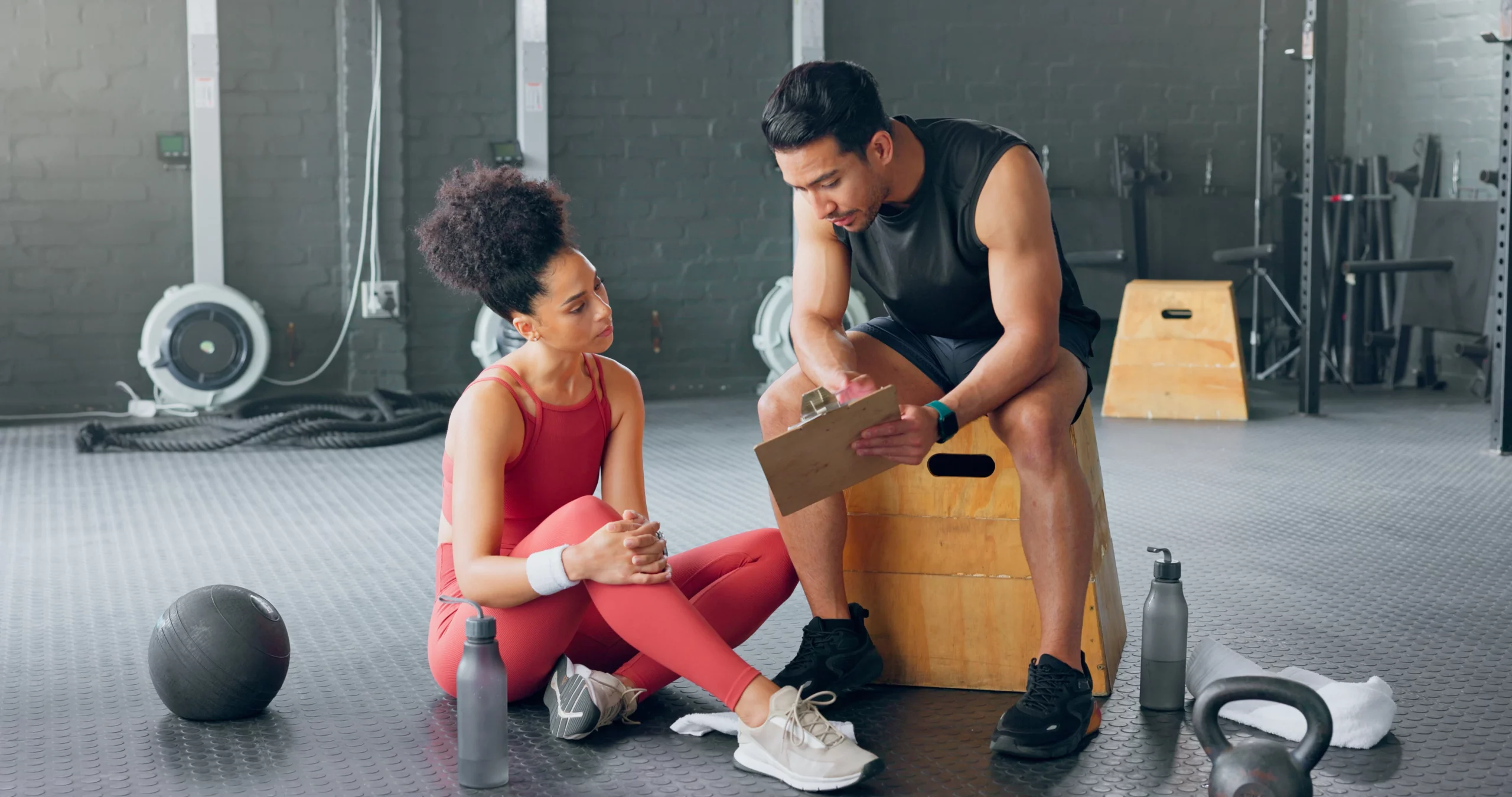 Two trainers review resources in a gym.