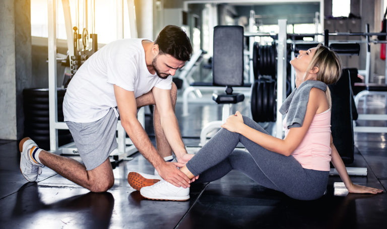 A fitness instructor is assisting a client who injured her ankle during a workout.