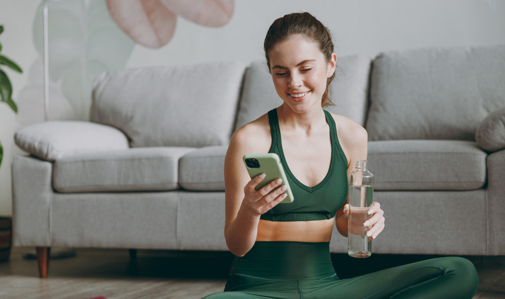 A personal trainer is on her phone smiling.