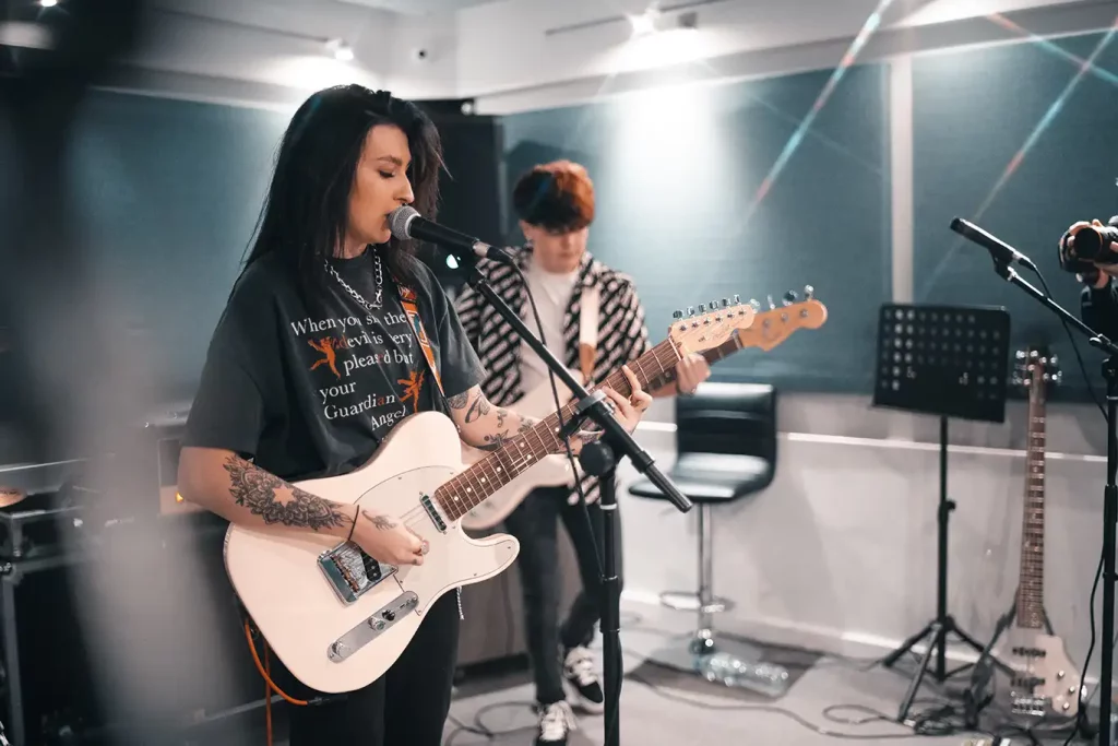 Two band members playing their song in a recording studio
