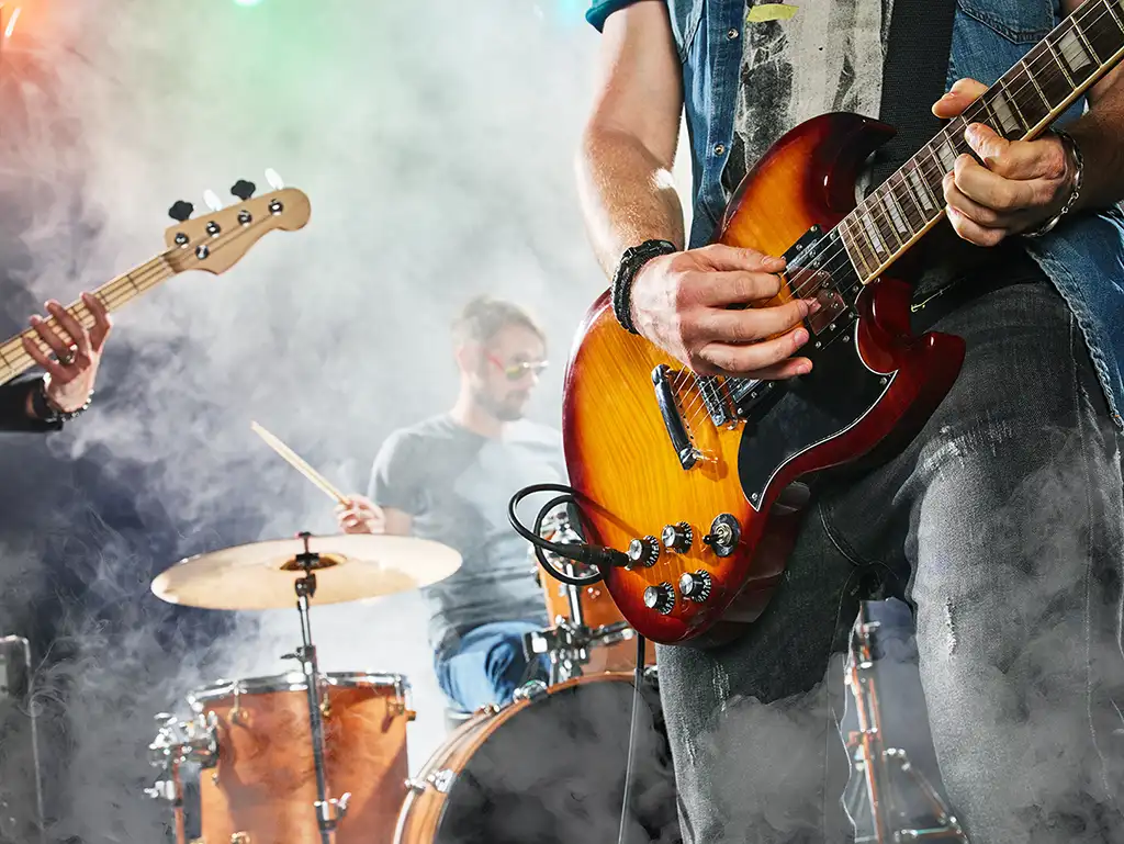 A band playing in smoke, the focus placed on a guitar player