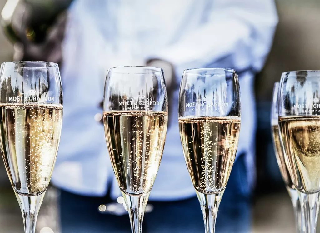 A close-up shot of four glasses of champagne at an outdoor event.