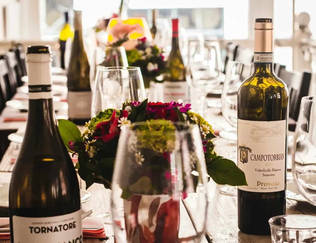 Bottles of wine on a table at an event surrounded by floral centerpieces.