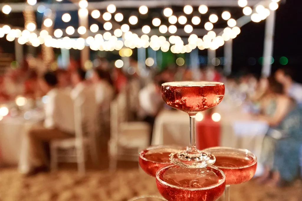 A close-up shot of a pyramid made from glasses of pink champagne on a table at a wedding reception.