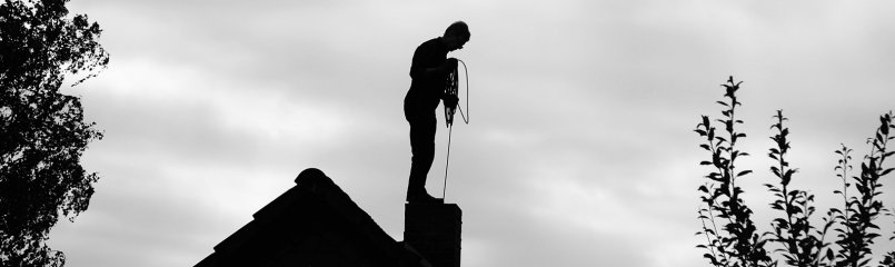 man chimney sweeping on roof
