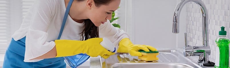 woman carefully scrubbing sink