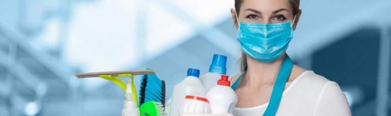 woman wearing a mask holding cleaning supplies