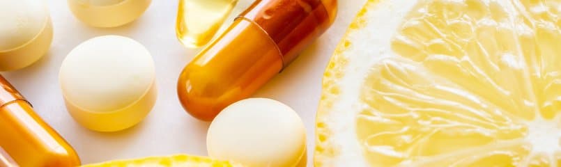 vitamins and supplements next to a sliced lemon