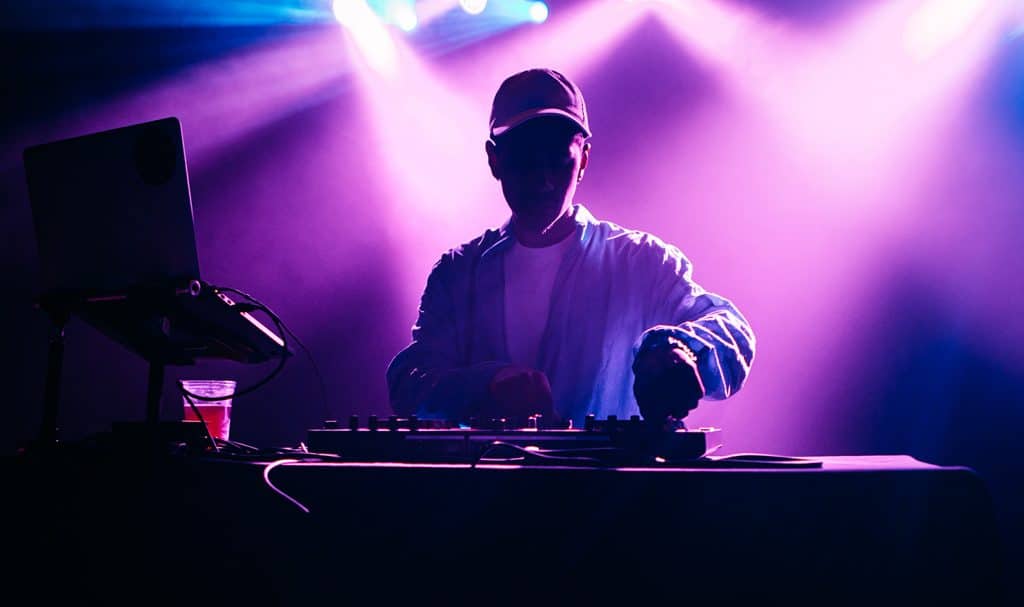 silhouette of DJ mixing with purple lights in the background