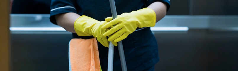 A person with cleaning gloves and cleaning supplies.