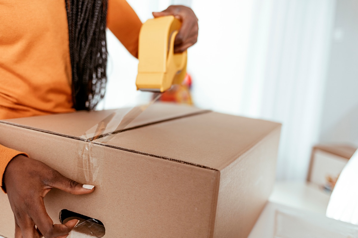 A woman places a product into a cardboard shipping box