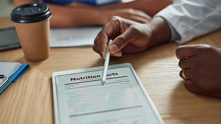 Nutrition facts displayed on a tablet, pointed to by a nutritionist with a stylus.