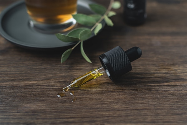 Cannabis Business Insurance keeps this topical CBD oil insured. It sits on a countertop with an eyedropper full of oil.