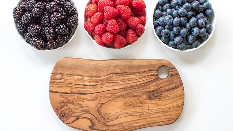 Bowls of berries and a cutting board.
