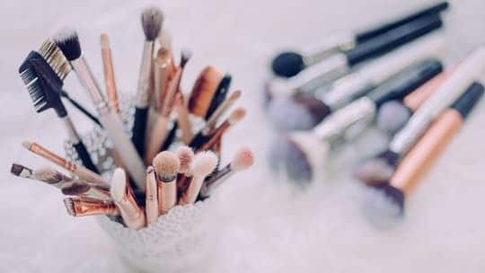 Cosmetic brushes and tools lay on a counter.