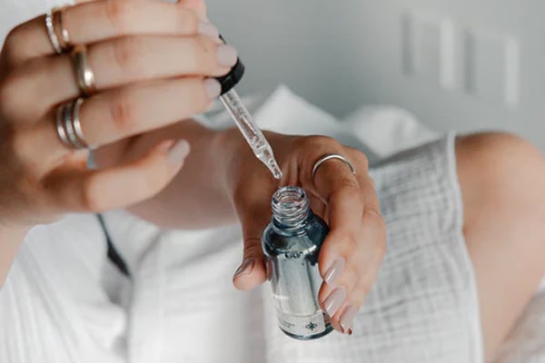 A consumer draws an oil in an eye-dropper with confidence because she buys skincare products that are insured with cosmetics product liability insurance.