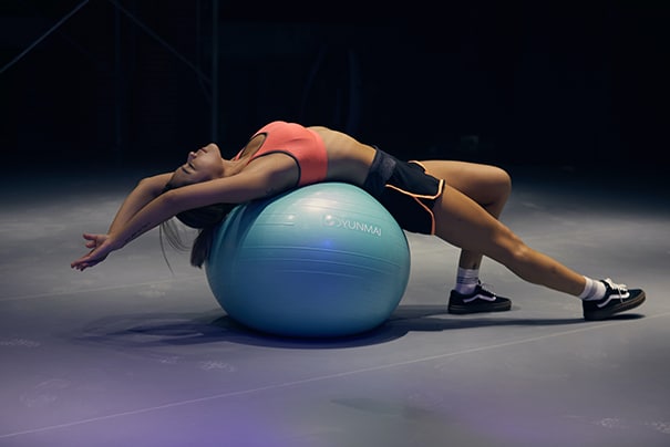 A woman stretches over an exercise ball while recovering from a workout. Her recovery may be aided by nutraceuticals insured with supplement liability insurance.