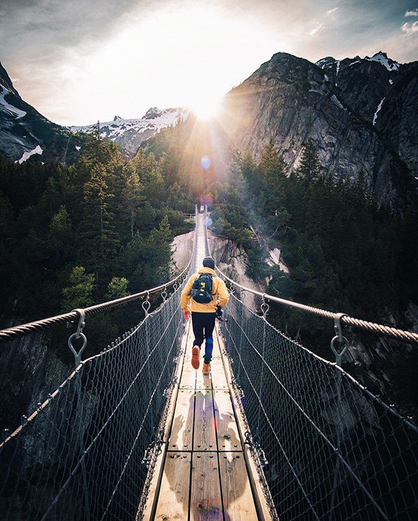 A jogger runs across a bridge on a beautiful hike with energy supplemented by vitamins insured with supplement liability insurance.