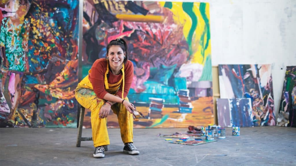 An artist poses in front of her work.