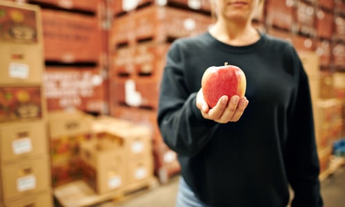 woman holding apple in warehouse