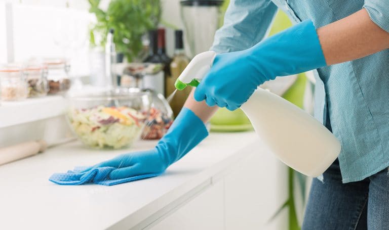 woman spraying counter with cleaning solution