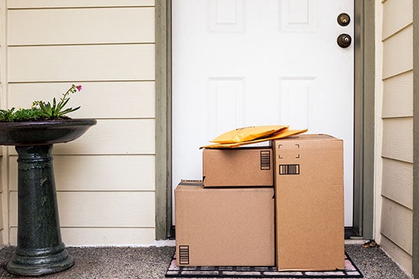 Stacks of packages are delivered to a customer at their front door.