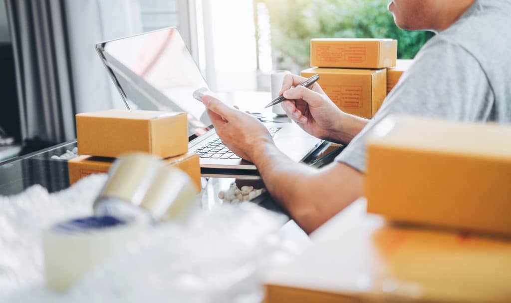 An eBay seller is surrounded by packages ready to be shipped as he purchases eBay liability insurance online from Insurance Canopy.