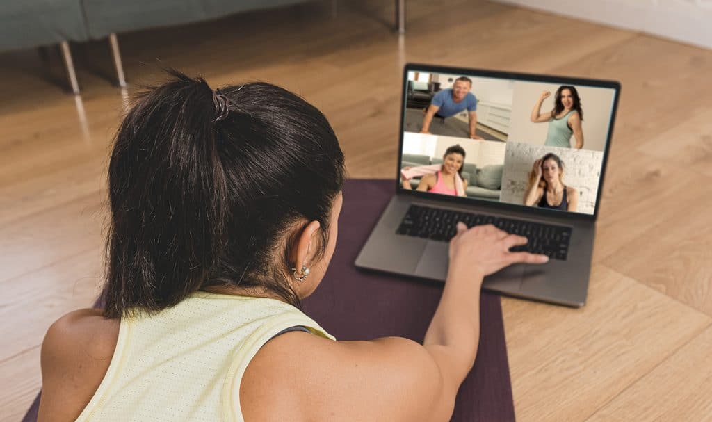 An online personal trainer is training clients from her home gym by livestreaming her class on her laptop.