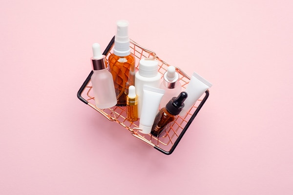 Shopping basket full of product bottles and packaging on pink background for a product insurance quote.