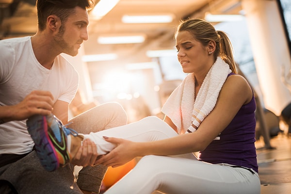 A personal trainer asks his client if she is okay after she injured her leg during a workout session, but luckily his fitness instructor insurance can cover this type of claim.