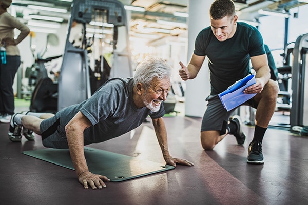 Personal trainer gives their elderly client a thumbs up as they complete a workout.