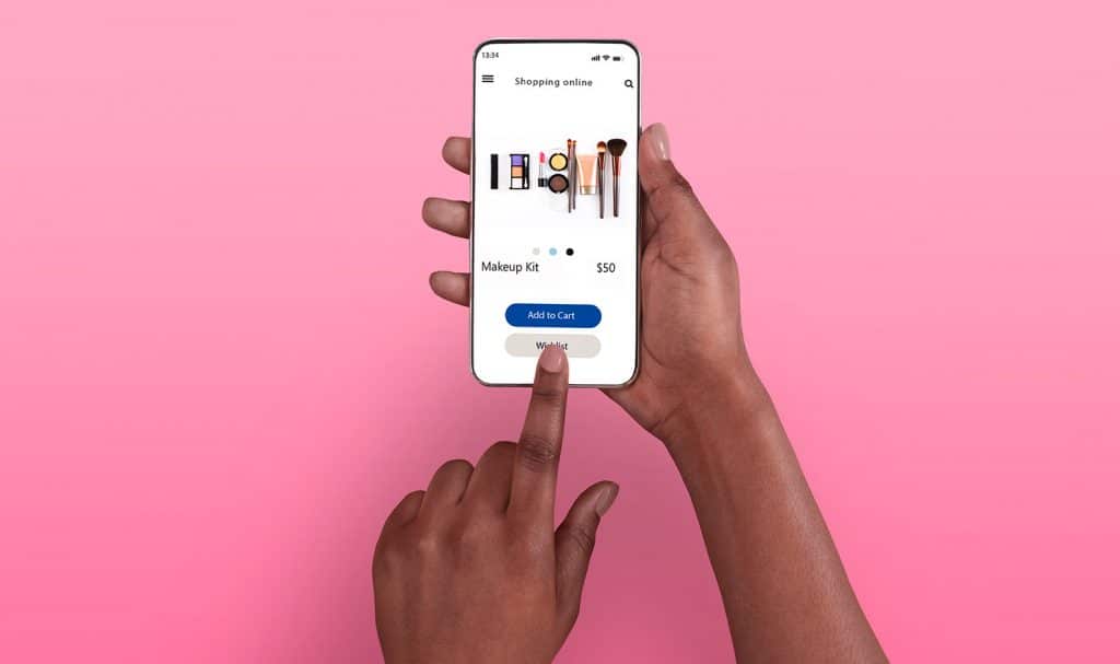 A person's hands hold a smart phone over a pink background and is testing out the purchase product feature on their new website.