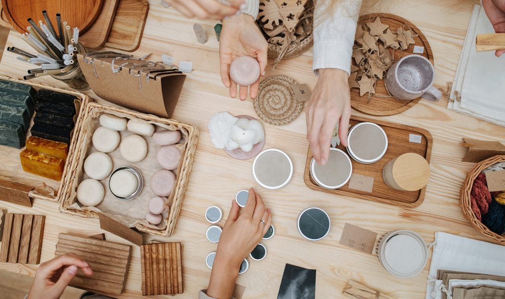 A group of people sit around a table full of beauty and skincare products they make as part of their own business.